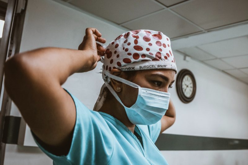 A female surgeon wearing a surgical mask and hat, ready to perform a medical procedure.